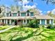Charming teal two-story home with white trim, dormers, and a lovely front yard landscape at 8834 Whispering Oaks Trl, New Port Richey, FL 34654