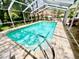 Enclosed pool area with clear blue water and patio furniture and screened enclosure at 8834 Whispering Oaks Trl, New Port Richey, FL 34654