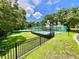 Exterior shot of the community tennis courts surrounded by lush greenery and secure fencing at 8834 Whispering Oaks Trl, New Port Richey, FL 34654
