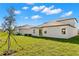 Large backyard, showcasing the new home's exterior, green grass, and new tree in the yard at 8918 Parsons Hill Blvd, Wesley Chapel, FL 33545