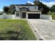 Charming two-story home featuring a stone accent entry, dark garage door and paver driveway at 9005 W Flora St, Tampa, FL 33615