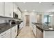 Long kitchen featuring stainless steel appliances, granite countertops, white cabinets, and a kitchen island at 10282 Echo Dock Loop, San Antonio, FL 33576