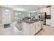 Open-concept kitchen with white cabinets, stainless appliances, and granite island that opens to the dining and living areas at 10282 Echo Dock Loop, San Antonio, FL 33576