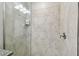 Modern shower with gray stone-like tile, glass doors, brushed metal fixtures, and a glass shelf at 10282 Echo Dock Loop, San Antonio, FL 33576