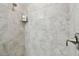 Modern shower featuring neutral stone-like tile, brushed metal fixtures, and a convenient glass shelf at 10282 Echo Dock Loop, San Antonio, FL 33576