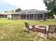 Backyard view featuring a fire pit, screened-in pool, and outdoor seating at 10287 Fordham St, Spring Hill, FL 34608