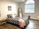Cozy bedroom featuring wood floors, a large window, and a comfortable-looking bed with decorative pillows at 10287 Fordham St, Spring Hill, FL 34608