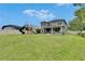 Backyard view of the house showing the covered patio, fire pit, playset, and ample green space at 10399 Boyette Brook St, Riverview, FL 33569