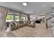 Comfortable living room showcasing a sectional sofa, large windows, and an open layout leading to the modern kitchen at 10399 Boyette Brook St, Riverview, FL 33569