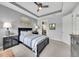 Cozy bedroom featuring tray ceiling, fan, and a view to the Primary bath at 10450 Highland Park Pl, Palmetto, FL 34221