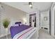 Bright bedroom with a purple accent wall, ceiling fan, and organized closet space at 10450 Highland Park Pl, Palmetto, FL 34221