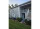 Two-story condominium exterior featuring a small yard and a staircase to the second level entrance at 12133 Spartan Way # 203, Hudson, FL 34667