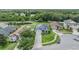 Overhead view of a suburban home featuring solar panels, manicured lawns, a serene pond, and tree-lined streets at 12251 Duckett Ct, Spring Hill, FL 34610