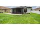 Charming backyard view showcasing the patio, screened-in porch, lush green lawn, and well-manicured landscaping at 12251 Duckett Ct, Spring Hill, FL 34610