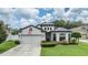 Charming home showcasing a well-manicured lawn, two-car garage, and a delightful blend of architectural styles at 12251 Duckett Ct, Spring Hill, FL 34610