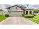 Home showcasing a two-car garage, well-kept lawn, and manicured shrubs, exemplifying suburban charm at 12251 Duckett Ct, Spring Hill, FL 34610