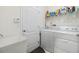 Laundry room with a white washer, dryer, laundry sink, and a shelf that provides storage for all laundry needs at 12251 Duckett Ct, Spring Hill, FL 34610