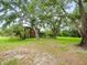 Spacious backyard featuring a lush green lawn, mature trees, and the home's exterior at 12603 Corral Rd, Tampa, FL 33626