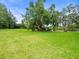 Large grassy backyard with mature shade trees, landscaping, and home exterior at 12603 Corral Rd, Tampa, FL 33626