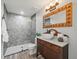 Bathroom featuring a stone-tiled shower and rustic wooden vanity with modern fixtures at 12603 Corral Rd, Tampa, FL 33626