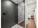 Modern shower with dark gray tile, glass partition, and white hexagon tile floor at 12603 Corral Rd, Tampa, FL 33626