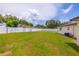 Well-kept backyard featuring lush green grass, white fencing, and some trees at 12877 Palm Dr, Largo, FL 33774