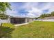 Spacious backyard with a well-maintained lawn, privacy fence, and screened-in patio at 12877 Palm Dr, Largo, FL 33774