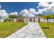 View of a well-manicured front yard, mature trees, and a stone-accented one story home at 12877 Palm Dr, Largo, FL 33774