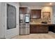 Modern kitchen with stainless steel refrigerator, dark wood cabinets, granite countertop, and door to pantry at 13102 Done Groven Dr, Dover, FL 33527