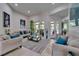 Bright living room featuring neutral-toned sofas with pops of blue, a glass coffee table, and sliding glass doors at 13102 Done Groven Dr, Dover, FL 33527