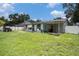Exterior view of home's backyard, showing the sunroom, patio, and grassy lawn at 15906 Country Farm Pl, Tampa, FL 33624