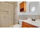 This bathroom has a step-in shower, a vanity, wood accents, and neutral-colored tiles at 1600 Amberlea N Dr, Dunedin, FL 34698