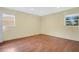 This is a bedroom with yellow walls, light-colored wood floors, and windows for natural light at 1600 Amberlea N Dr, Dunedin, FL 34698