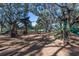 A well-maintained community playground with slides and play structures amid mature trees and mulch ground cover at 1600 Amberlea N Dr, Dunedin, FL 34698
