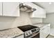 Modern kitchen featuring stainless steel appliances, range hood, granite countertops, and glossy white cabinetry at 16138 Manorwood Cir, Tampa, FL 33624
