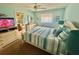 Light-filled bedroom showcasing soft blue walls, ceiling fan, dresser, and comfortable bedding at 1814 Driftwood S Cir, Oldsmar, FL 34677