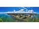 Wide-angle aerial view of waterfront community featuring stunning blue water, white clouds, and lush greenery at 1951 Edgewater Dr, Clearwater, FL 33755