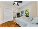 Bright bedroom featuring hardwood floors, ceiling fan, and sunlit window with view of backyard at 1951 Edgewater Dr, Clearwater, FL 33755