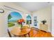 Bright dining area with hardwood floors, arched windows overlooking the water, and a decorative flower arrangement at 1951 Edgewater Dr, Clearwater, FL 33755