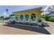 Bright yellow home featuring arched windows with brick paved driveway and manicured landscaping at 1951 Edgewater Dr, Clearwater, FL 33755