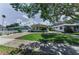 Charming yellow house features a lush green lawn, a brick driveway, and mature trees offering a picturesque setting at 1951 Edgewater Dr, Clearwater, FL 33755