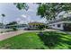Inviting yellow house with lush green lawn, brick driveway, and mature trees creating a picturesque setting at 1951 Edgewater Dr, Clearwater, FL 33755