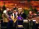 Vibrant performance by a band featuring a saxophone player, guitarist, and drummer under bright lights at 1951 Edgewater Dr, Clearwater, FL 33755