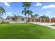 Lush green backyard featuring a putting green, pool, and covered patio, all set against a backdrop of palm trees at 1964 Tanglewood Ne Dr, St Petersburg, FL 33702