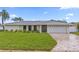 Well-manicured lawn and landscaping highlight this home's brick driveway and white exterior at 1964 Tanglewood Ne Dr, St Petersburg, FL 33702
