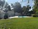 Expansive backyard featuring green grass, a sparkling pool, an outdoor seating area, and mature shade trees at 2005 Capri Rd, Valrico, FL 33594