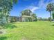 Large backyard with lush green grass, a screened porch, and a fenced yard for privacy at 20352 Astoria Ave, Port Charlotte, FL 33952