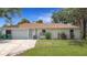 Charming single-story home with a well-maintained lawn and attached garage on a sunny day at 20352 Astoria Ave, Port Charlotte, FL 33952