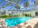 Screened-in pool with brick paver deck and lush landscaping surrounding the enclosure at 20352 Astoria Ave, Port Charlotte, FL 33952