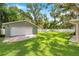 Large, grassy backyard featuring a detached garage, picnic table, and a white picket fence at 205 W Wheeler Rd, Seffner, FL 33584